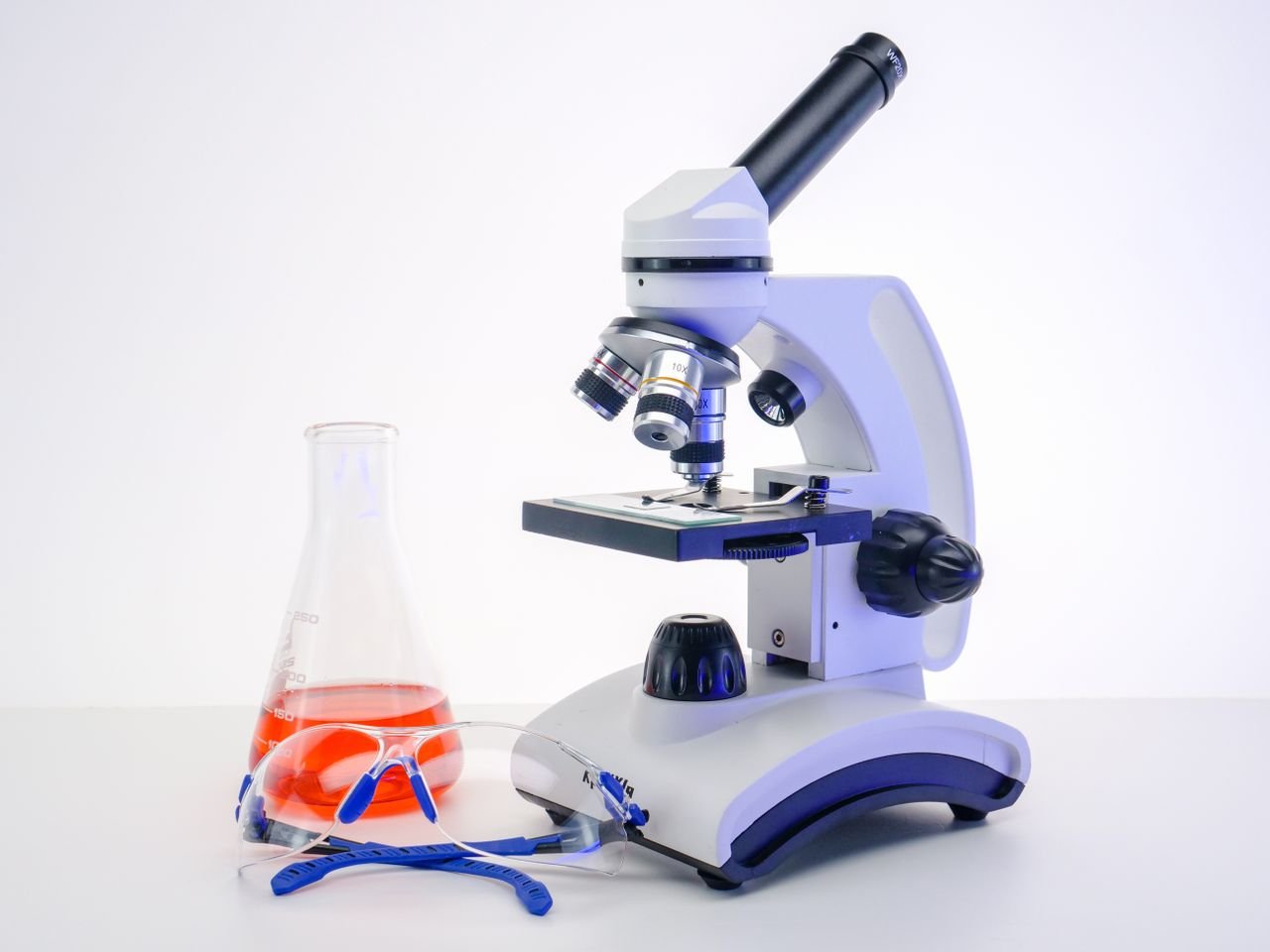Microscope and flask with red liquid in laboratory setting. Perfect for science-themed projects.